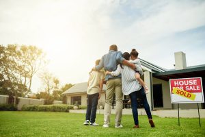 The backside of a family facing a newly bought home